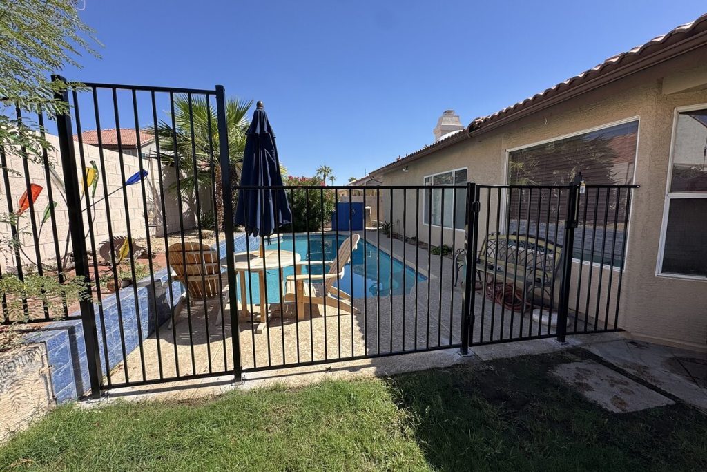 Black iron pool fence and self-latching gate enclosing a backyard pool