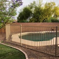 white iron pool fence attached to stone wall barrier